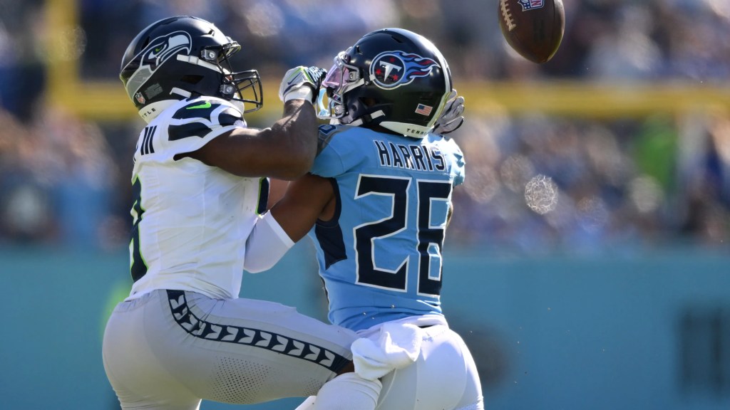 A Seattle Seahawks player attempts to tackle a Tennessee Titans player who is catching a football during an NFL game.